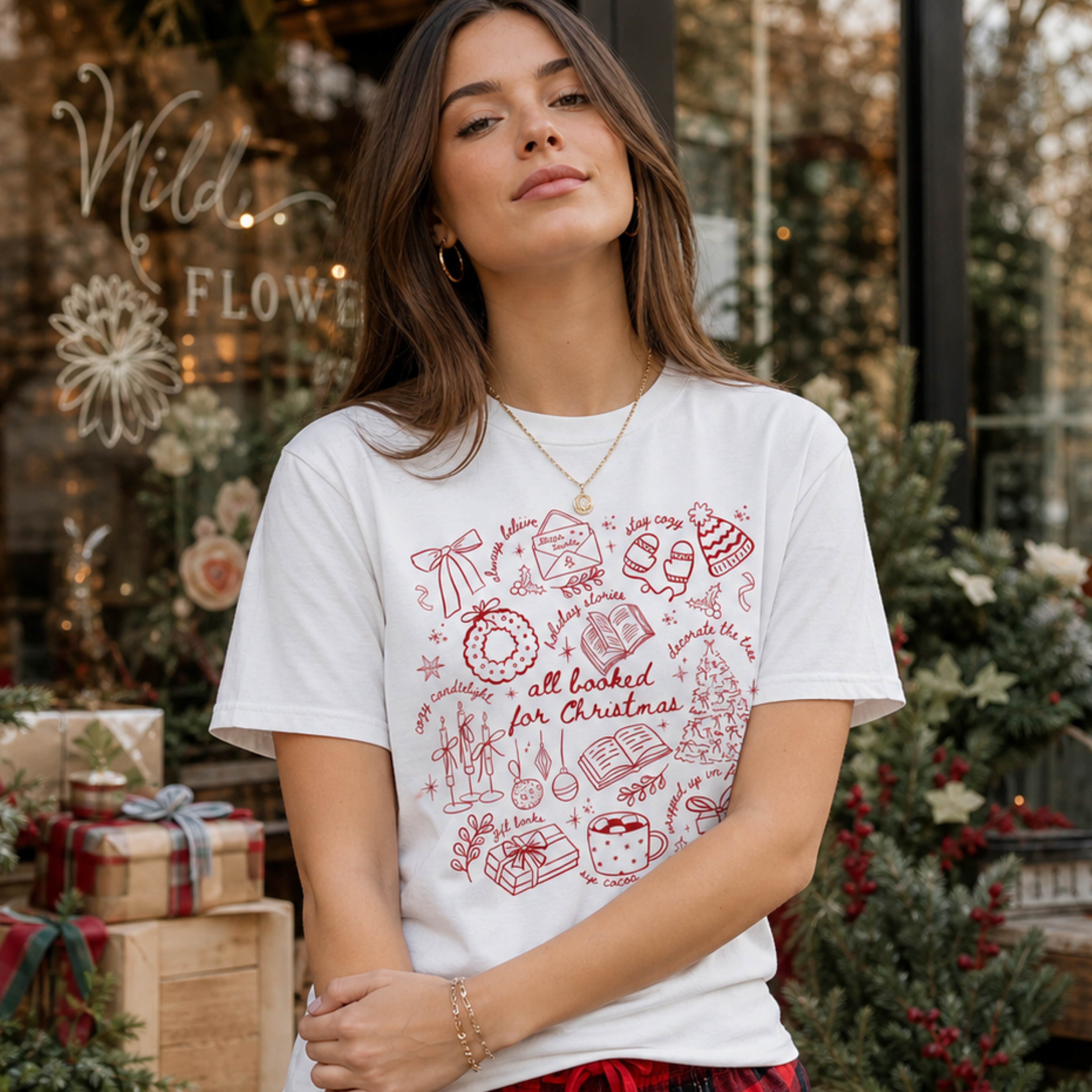 Lifestyle photo of the All Booked for Christmas Comfort Colors graphic T-shirt featuring Christmas doodles and book lover design.