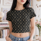 Woman wearing a celestial moon and sun crop tee with an all-over astrology print in a cozy boho-inspired setting.