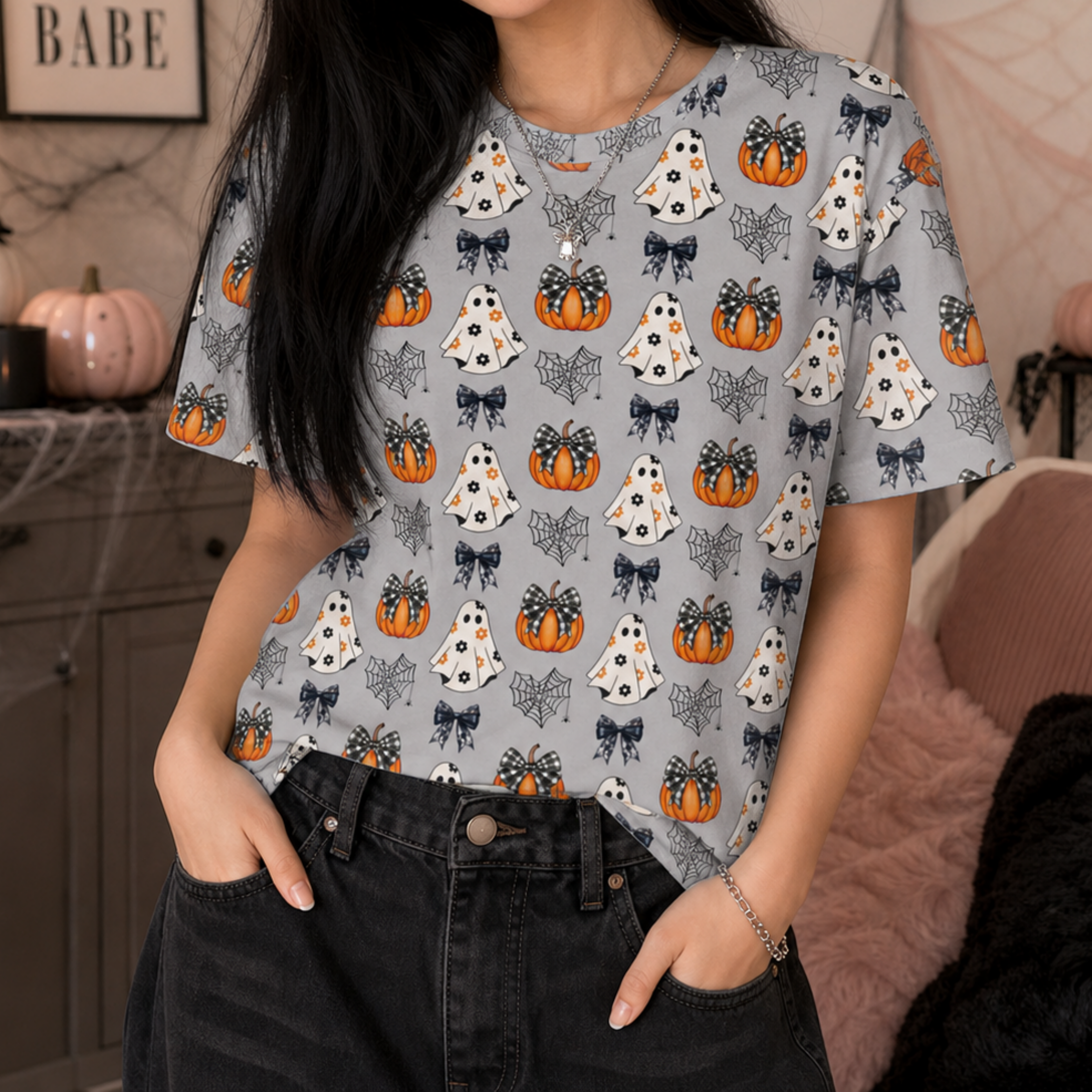 Close-up of a Halloween all over print T-shirt featuring cute ghosts, pumpkins, bows, and spiderweb patterns.