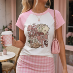Woman wearing a coquette lucky casino baby tee with pink raglan sleeves featuring vintage playing cards, bows, horseshoes and floral artwork.
